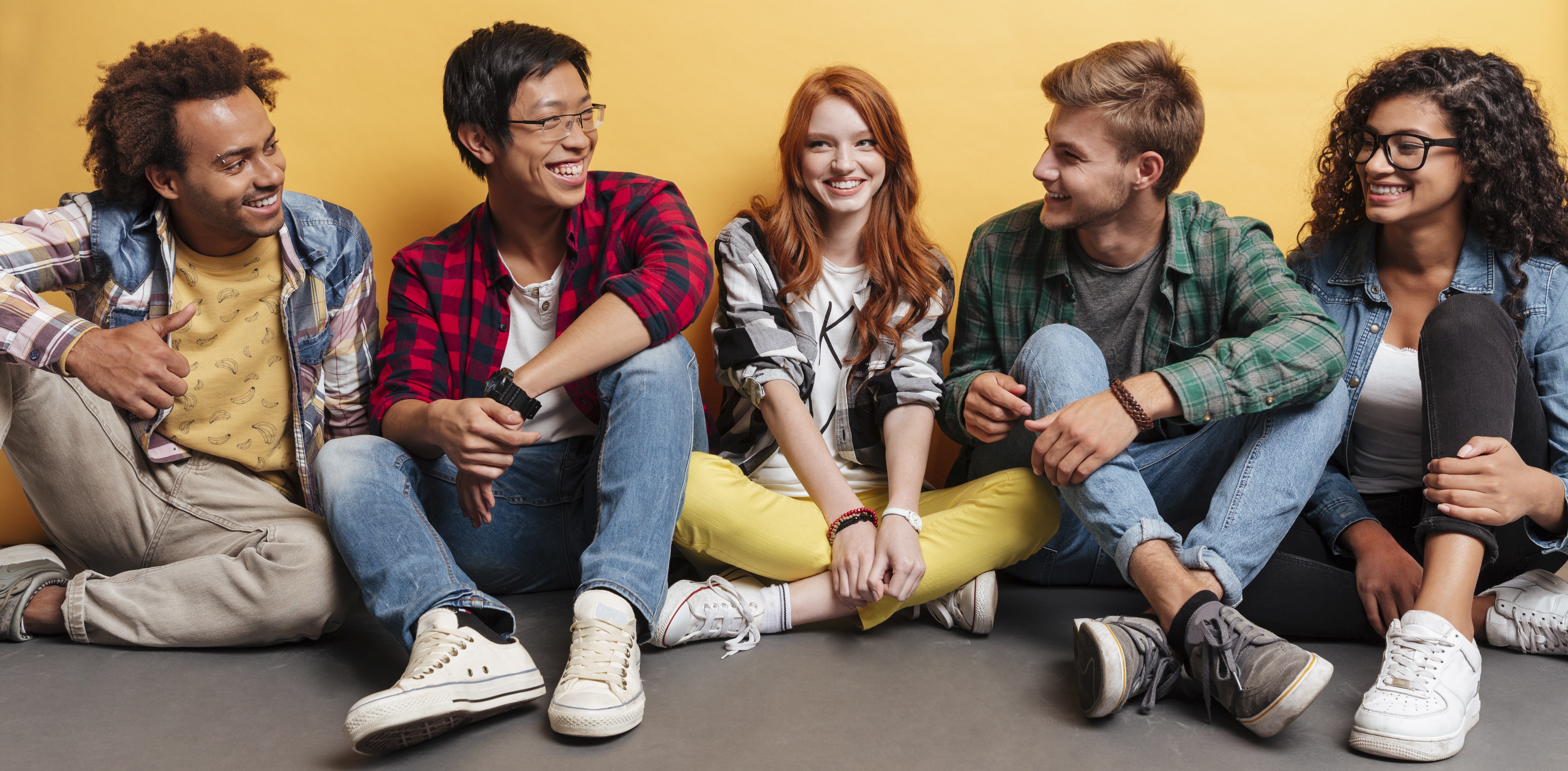 group of diverse teens sitting on the floor smiling