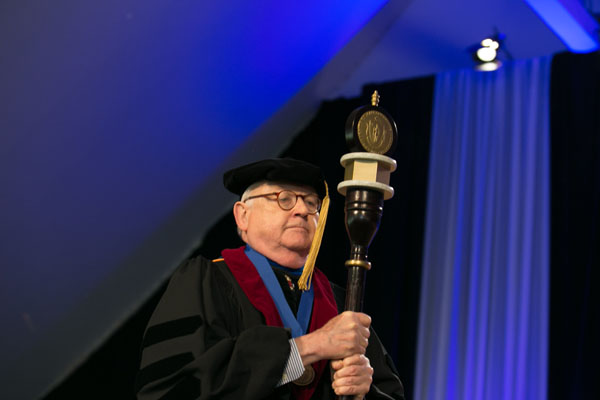 Thoru Pederson, PhD, carries the mace and leads the processional.