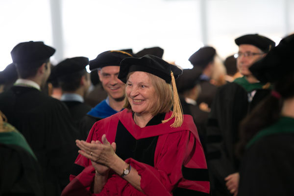 Nancy Bennet, MD, applauds the graduates as she processes into the tent.