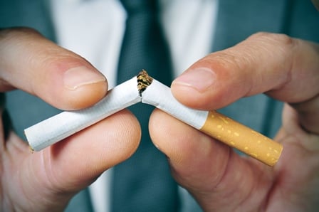 a man in a business suit breaking a cigarette in half