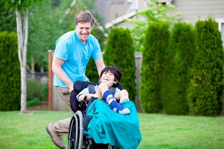 father running and pushing son in wheelchair laughing