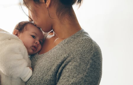 woman holding newborn and kissing it on the head