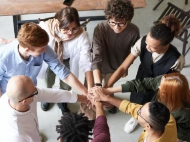 group of business people in a circle with their hands stretched out together