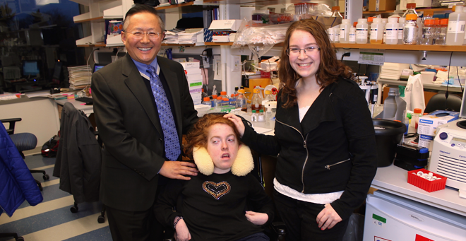 Rachel Epstein, center, visits Guangping Gao, PhD, and intern Jessica Epstein, her sister, at Dr. Gao’s lab in 2014.