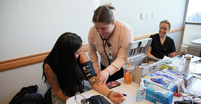 Three people at a table with medical supplies